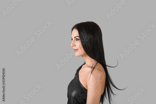 Young woman with beautiful healthy hair on grey background