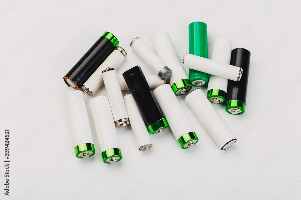 Naklejka premium many new and used alkaline the positive ends of battery cells. type AA on a light background.
