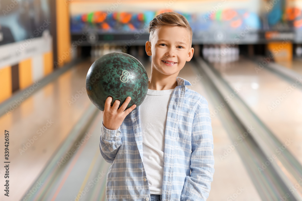 Naklejka premium Little boy playing bowling in club