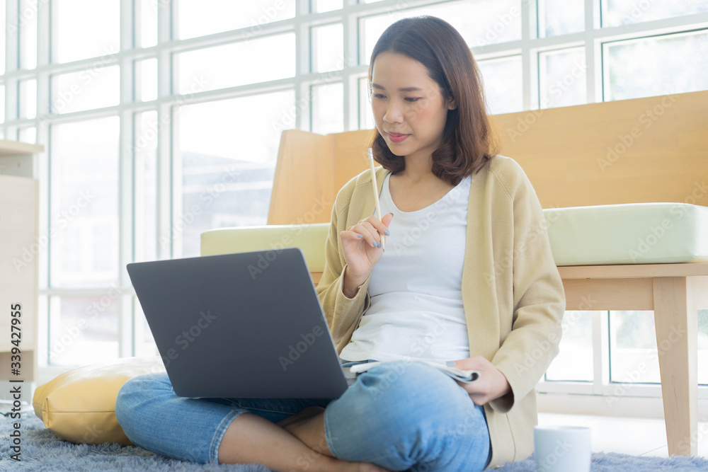 close up young woman leaning sofa and sitting on he floor and using laptop to learning online course in house for quarantine activities and lifestyle concept