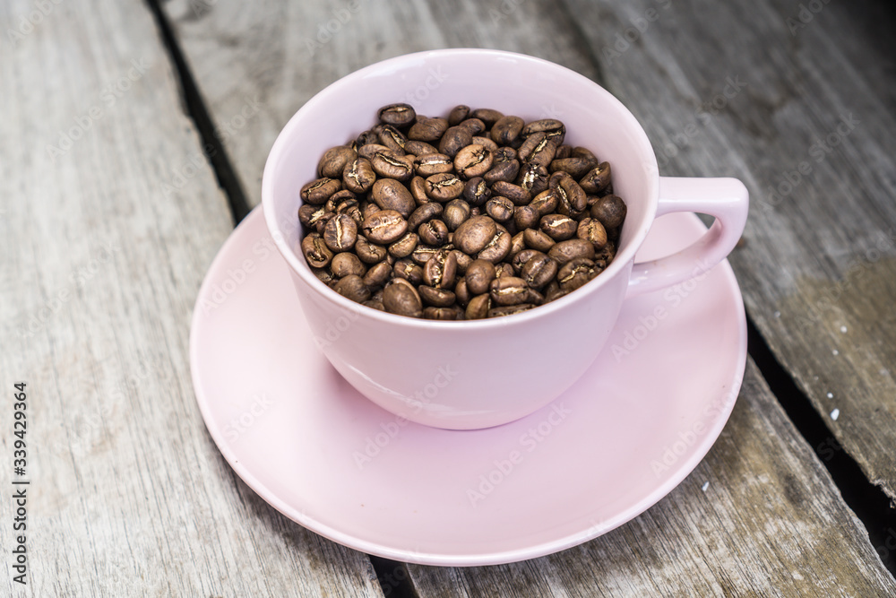 Close up of coffee beans in a cup, on a wooden table. Close up of coffee beans in a cup, on a wooden table.