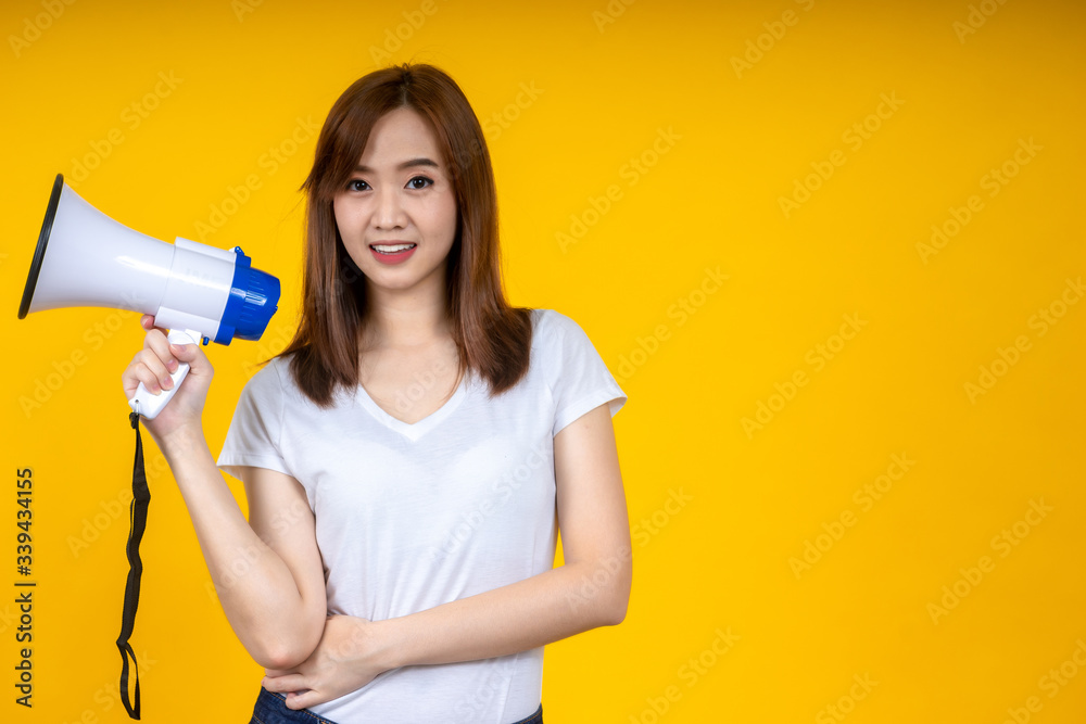 Young Asian woman in white casual t-shirt looking aside, scream in megaphone isolated on bright yellow wall background in studio. People lifestyle concept. Mock up copy space Young Asian woman in white casual t-shirt looking aside, scream in megaphone isolated on bright yellow wall background in studio. People lifestyle concept. Mock up copy space
