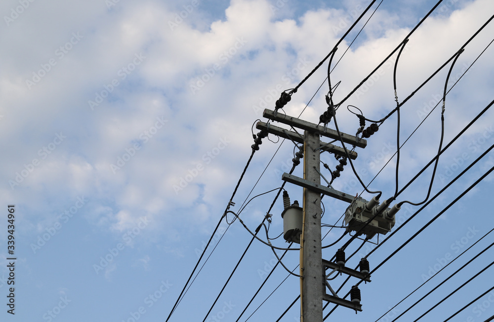 Closeup of electricity wire, cable, poles and high voltage transformer beside the street with cloudy blue sky background. 