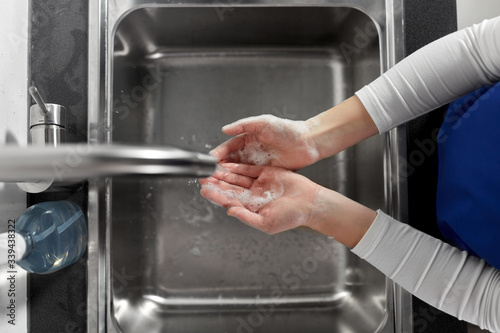 hygiene, health care and safety concept - close up of female doctor or nurse washing hands with soap and water at hospital