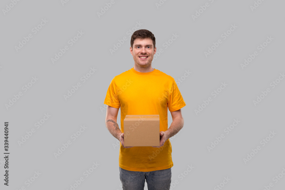 Delivery Man with Box in Hands. Yellow Tshirt Delivery Boy. Home Delivery. Quarantine Hero. Man Smiling