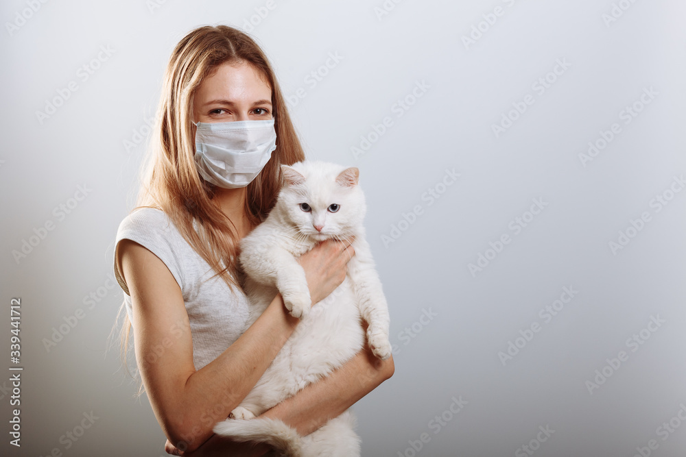 Woman in protective surgical mask holds cat pet in face mask. Chinese Coronavirus disease COVID-19 is dangerous for pets Woman in protective surgical mask holds cat pet in face mask. Chinese Coronavirus disease COVID-19 is dangerous for pets
