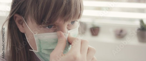 Woman put on surgical face mask staying home during coronavirus covid 19 virus outbreak close up