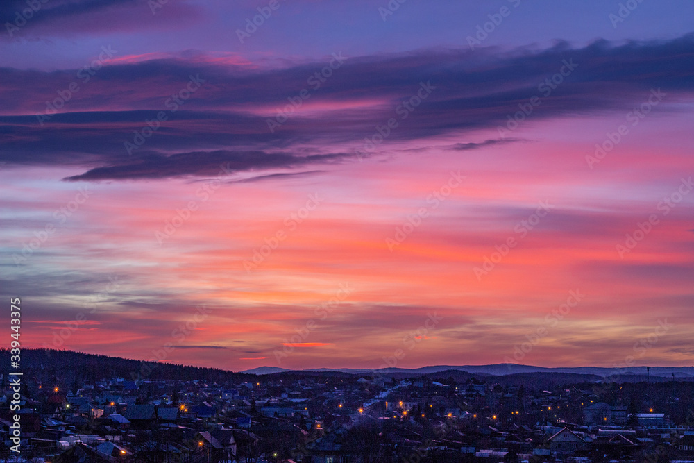 Beautiful purple sunset over the night city. Bright orange sunset in the evening city. Bright lights of urban houses. Soft focus. Russia, Ural