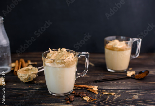 Delicious and fragrant dalgona coffee in glass cups, cinnamon sticks, dried mushrooms, a spoon of instant coffee, sugar.