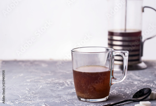 Coffee with milk in a glass cup, spoon, sugar, custard, a bottle of milk on a glass background.