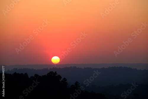 Beautiful sunset over a misty mountains. View of valley with silhouette of mountains ridge on backdrop.