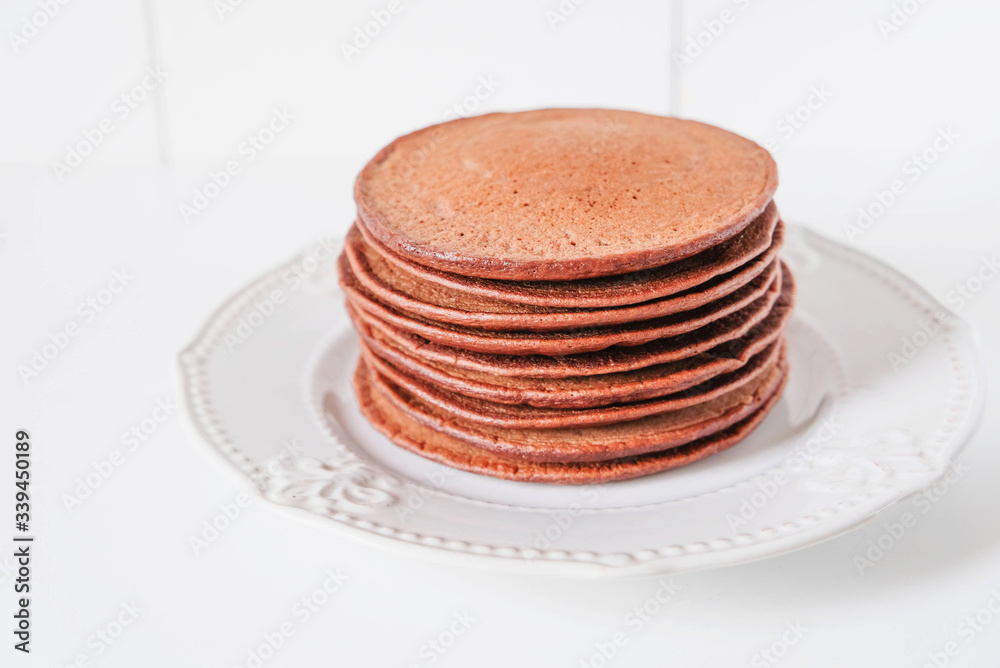 Sugar free protein chocolate pancakes stacked on white plate.