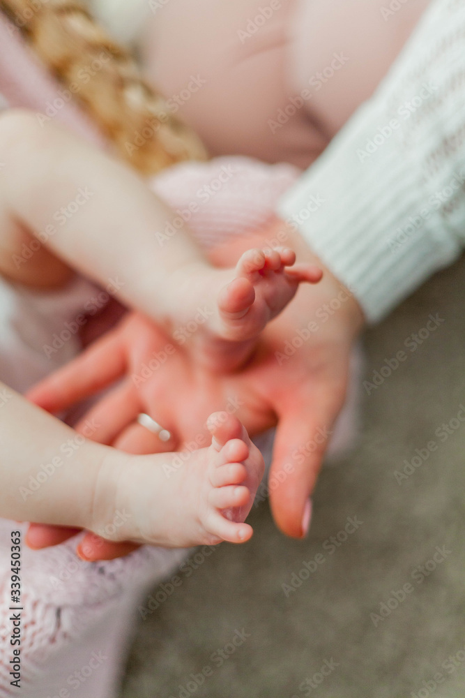 Close-up. Beautiful young mother holds in her hands the legs of her little daughter. Baby. Newborn. Close-up. Beautiful young mother holds in her hands the legs of her little daughter. Baby. Newborn.