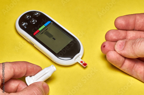 A diabetic checks his blood sugar. Close up man hands self-tested with a Lancet and a glucometer at home.