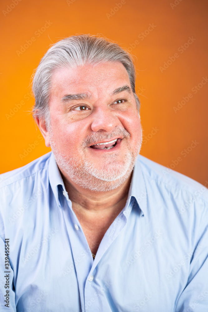 Man headshot portrait. He is happy. He is smiling and looking to one side. The background is lighted with orange color. Man headshot portrait. He is happy. He is smiling and looking to one side. The background is lighted with orange color.