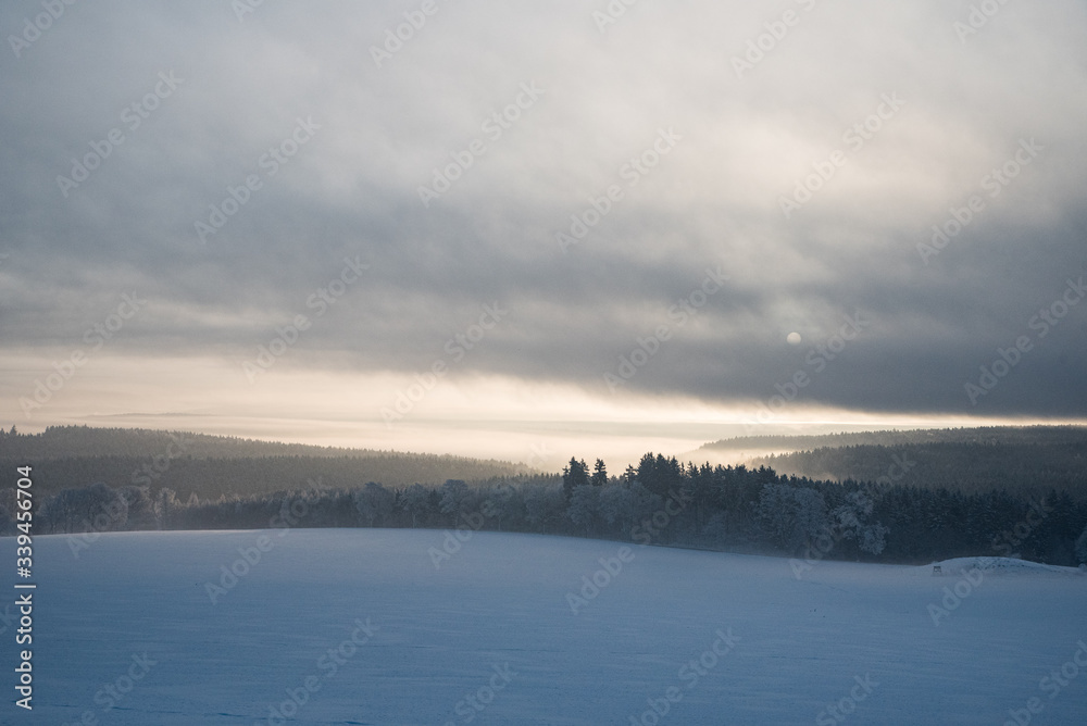 relaxing overcast moudy clouds in a winter valley while sunrise and sundown in a uphill winter scenery with field trees and forest relaxing overcast moudy clouds in a winter valley while sunrise and sundown in a uphill winter scenery with field trees and forest