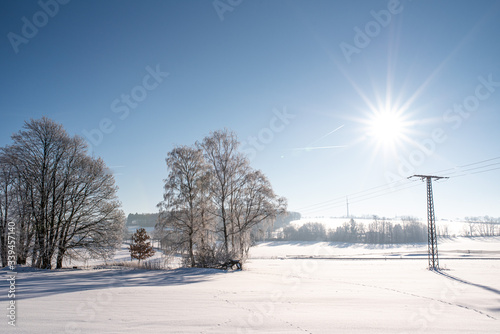 Feld im Winter mit Schneedecke, Sonnenschein und blauem Himmel