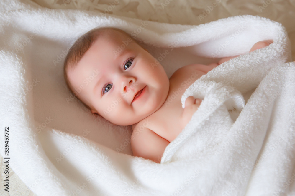 baby is wearing diapers and a white towel in bedroom. A newborn baby is resting in bed after a bath or shower. Children's room. Textiles and bedding for children. baby is wearing diapers and a white towel in bedroom. A newborn baby is resting in bed after a bath or shower. Children's room. Textiles and bedding for children.