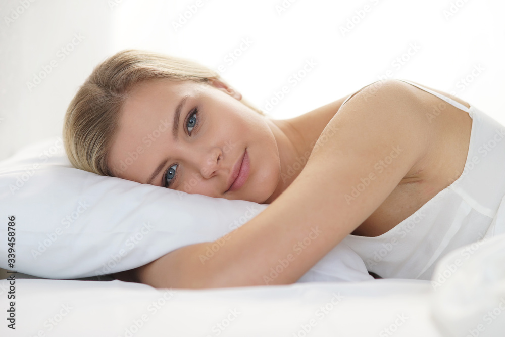 Young woman lying in the bed. Beautiful blond sleeping girl. Morning in the bedroom, daylight from the window. Health and rest. Young woman lying in the bed. Beautiful blond sleeping girl. Morning in the bedroom, daylight from the window. Health and rest.