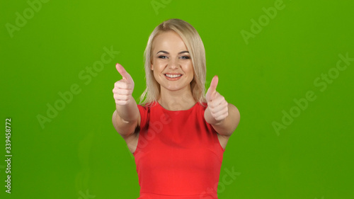 Happy blonde shows gesture all right with both hands. Studio