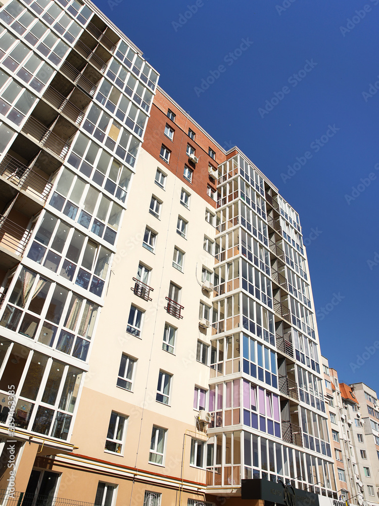 Lviv, Ukraine - 3 4 2020: Facade of a tall multi-storey modern house with balconies and large glass windows. Design of modern architecture. Top view from the bottom. Modern city architecture