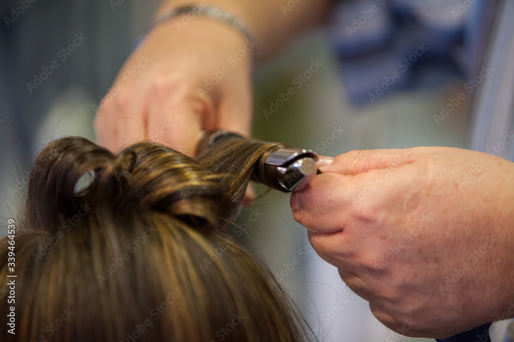 Obraz premium Hairdresser doing a woman's hair in professional hairdressing salon or barbershop , seen from behind the customer, unrecognizable.