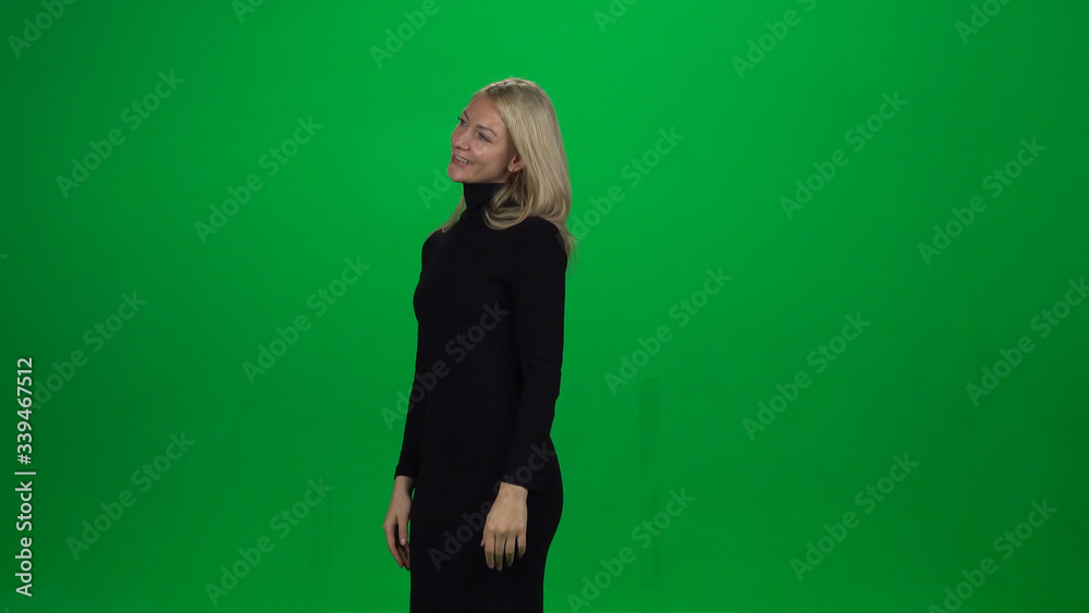 Young female is standing with tender smile. Green screen