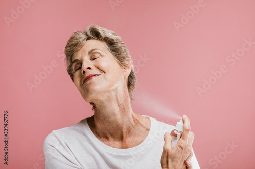Senior woman spraying perfume