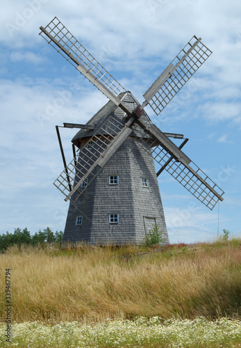 Traditioinal Swedish windmill on summer meadow  blue cloudy sky. 