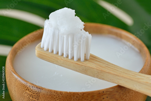 Coconut oil in a bowl with a wooden toothbrush - Homemade whitening toothpaste photo