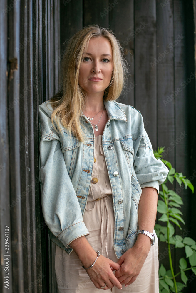vertical close-up portrait of a sad blonde on a background of an old wooden building vertical close-up portrait of a sad blonde on a background of an old wooden building