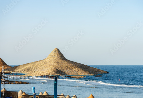 Straw umbrellas in a Red Sea beach  near Marsa Alam  Egypt  Africa. The waves of the sea crash on the coral reef