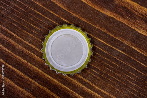 bottom view of a metal cork with copyspace isolated on a wooden background. Cover blank cap on wood table, canned meal