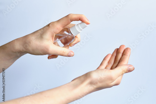 Hand holds a sanitizer - an antiseptic and sprays on the hand - concept of protection against coronavirus COVID-19.