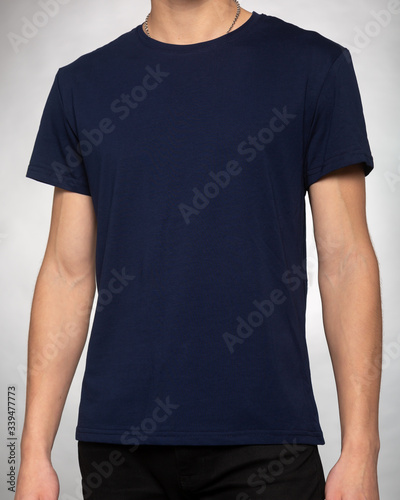 guy in a dark blue plain t-shirt clothes stands with his hands down on a light gray background