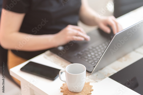 Young woman working at her office desk with documents and laptop with a cup of coffee on the table
