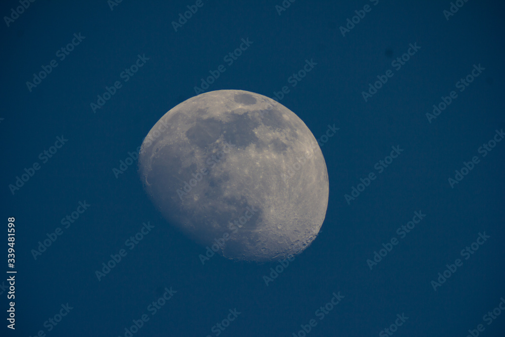 The moon in the telescope in the evening on a dark blue sky background The moon in the telescope in the evening on a dark blue sky background