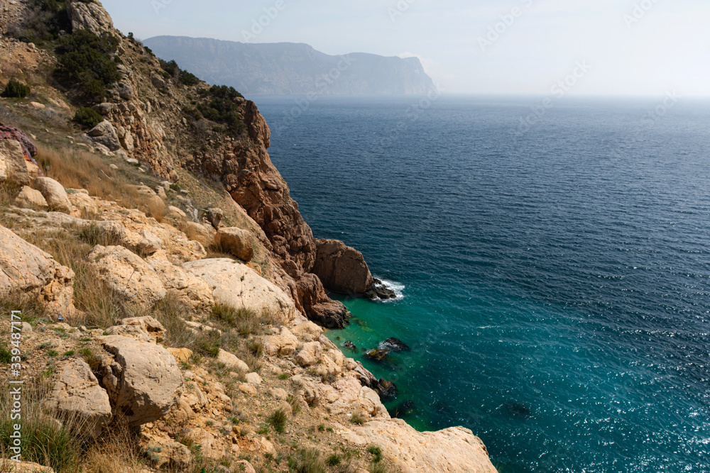 The turquoise sea and cliff top view of the Crimean coast, the tourist season, the trip to the Crimea, stone shore and beach