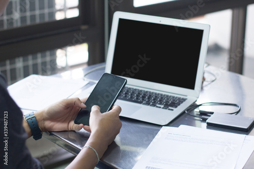 A man with a mobile phone playing And work at home through the office computer notebook