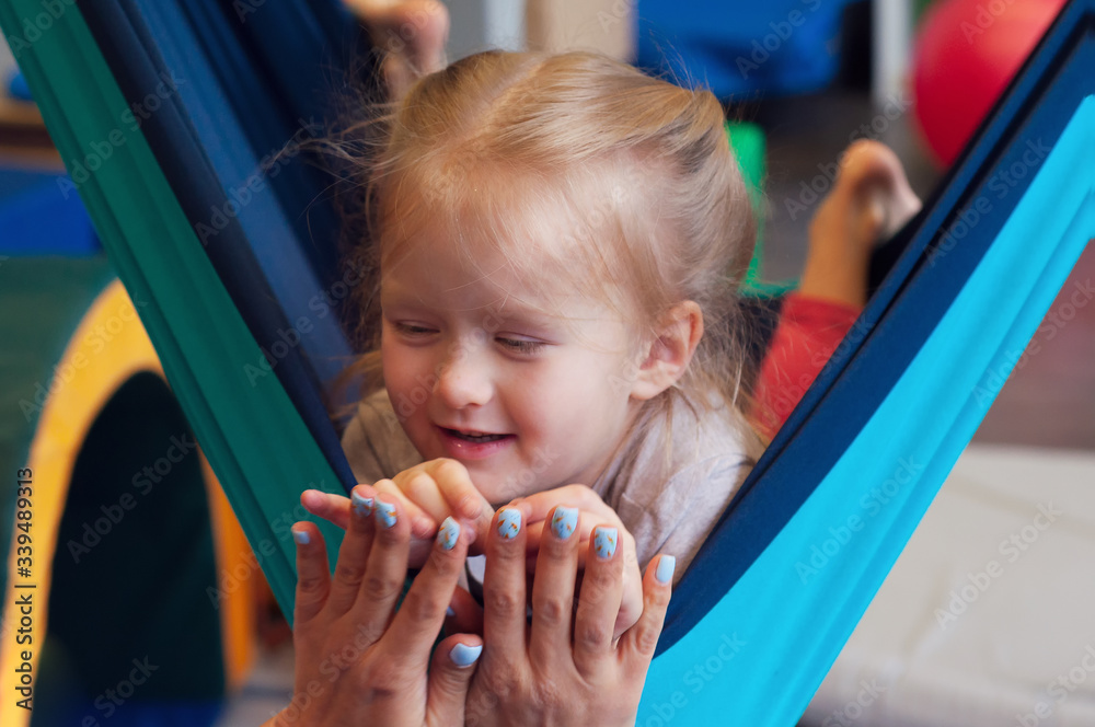 girl enjoying a sensory therapy on a hammock while physiotherapist