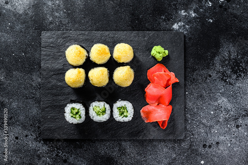Various kinds of sushi served on black stone. Black background. Top view