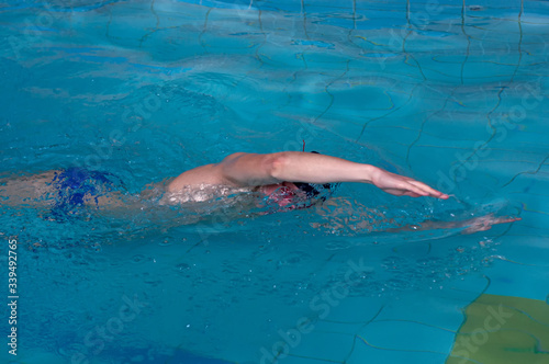 Man swims forward crawl style in swimming pool