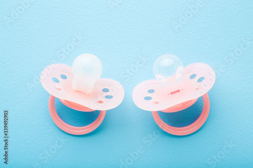 New and used silicone baby soothers on pastel blue table background. Compare before and after using. Regular change of hygiene products. Closeup. Top down view.