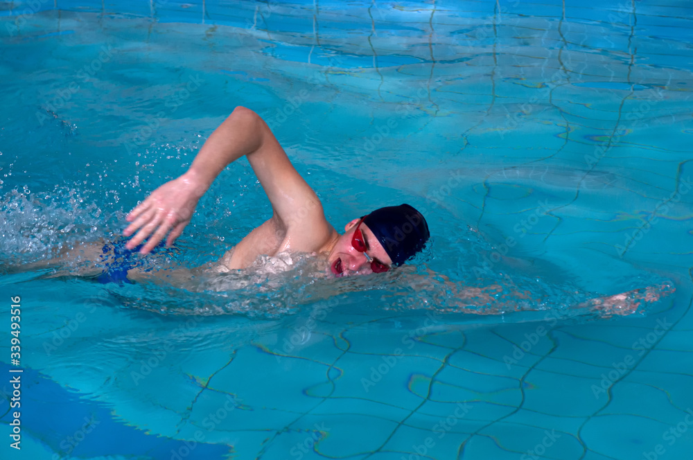 Man swims forward crawl style in swimming pool