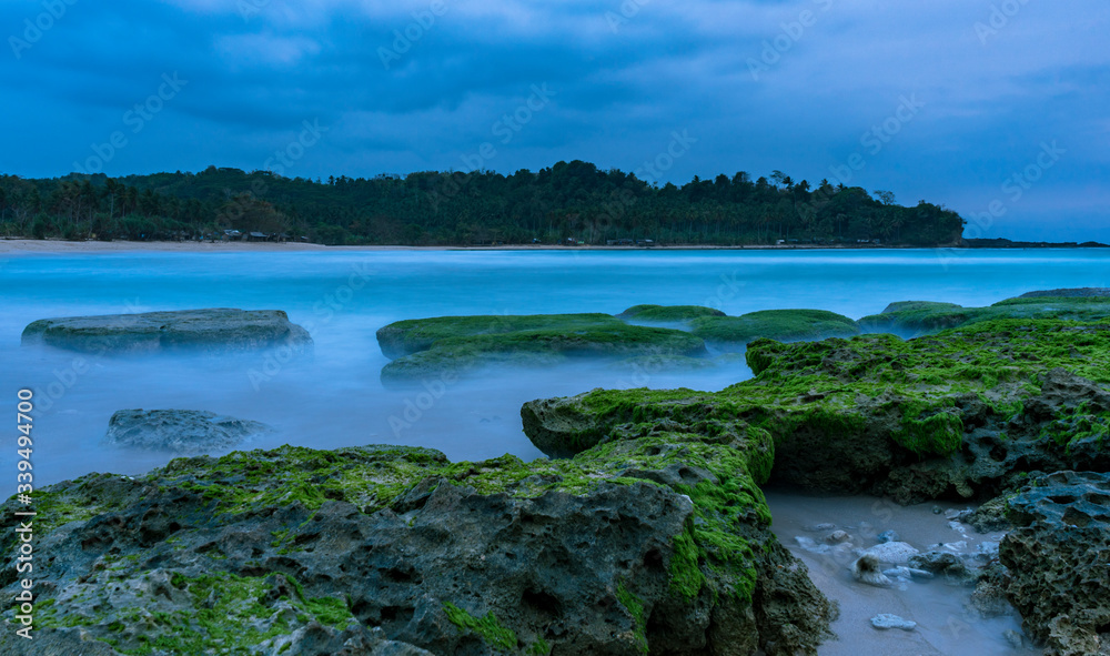 Beautiful evening dark sunset long exposure beach scene with rocks and Indian ocean in Sawarna, Banten, Java, Indonesia