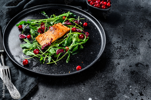 Seafood salad with trout, arugula, lettuce and cranberries. Black background. Top view. Copy space