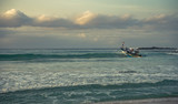 Small wooden traditional fishing boat is leaving beach through waves to open Indian ocean water in Java, Indonesia