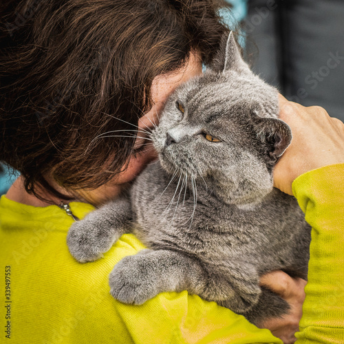 The woman hugs her gray cat tightly in her arms to express affection.