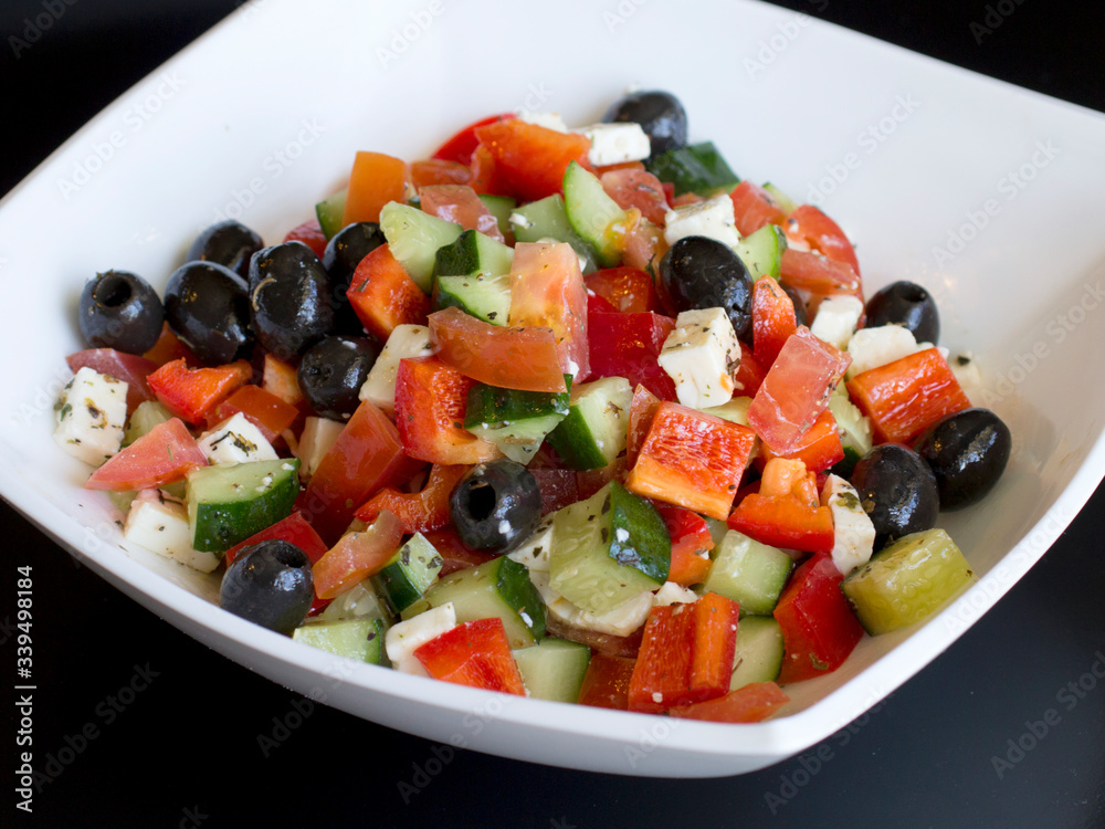 fresh greek salad in white plate on black table. vegetable salad with feta cheese. healthy food.