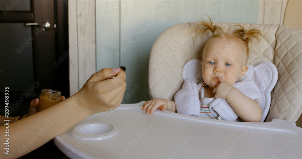 Caucasian mother feeding baby with spoon Caucasian mother feeding baby with spoon